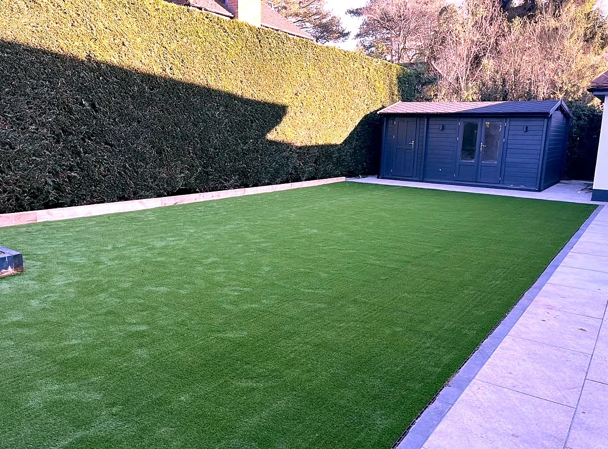 Artificial grass lawn with light paved edging and garden walls