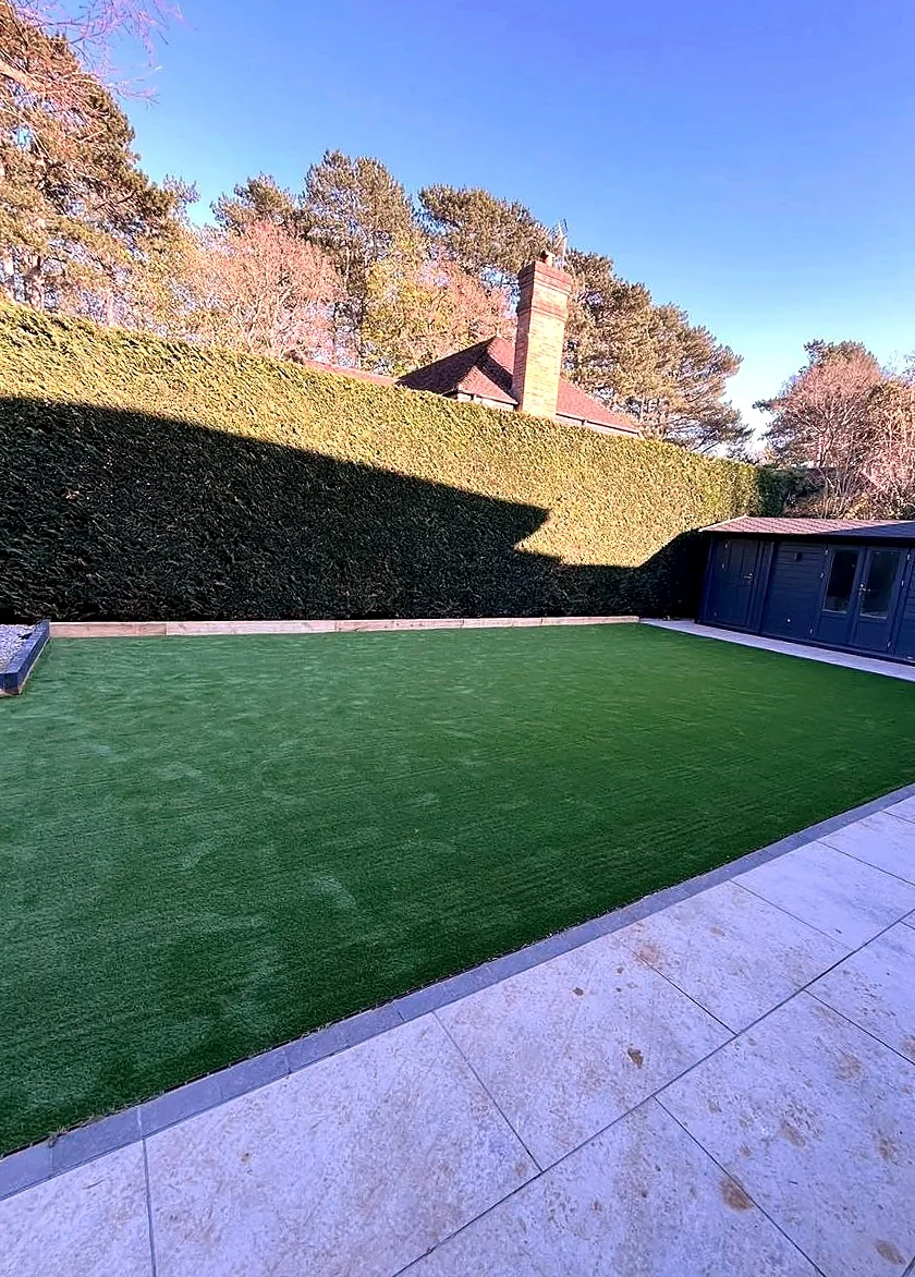 Artificial grass lawn edged with light silver paving slabs