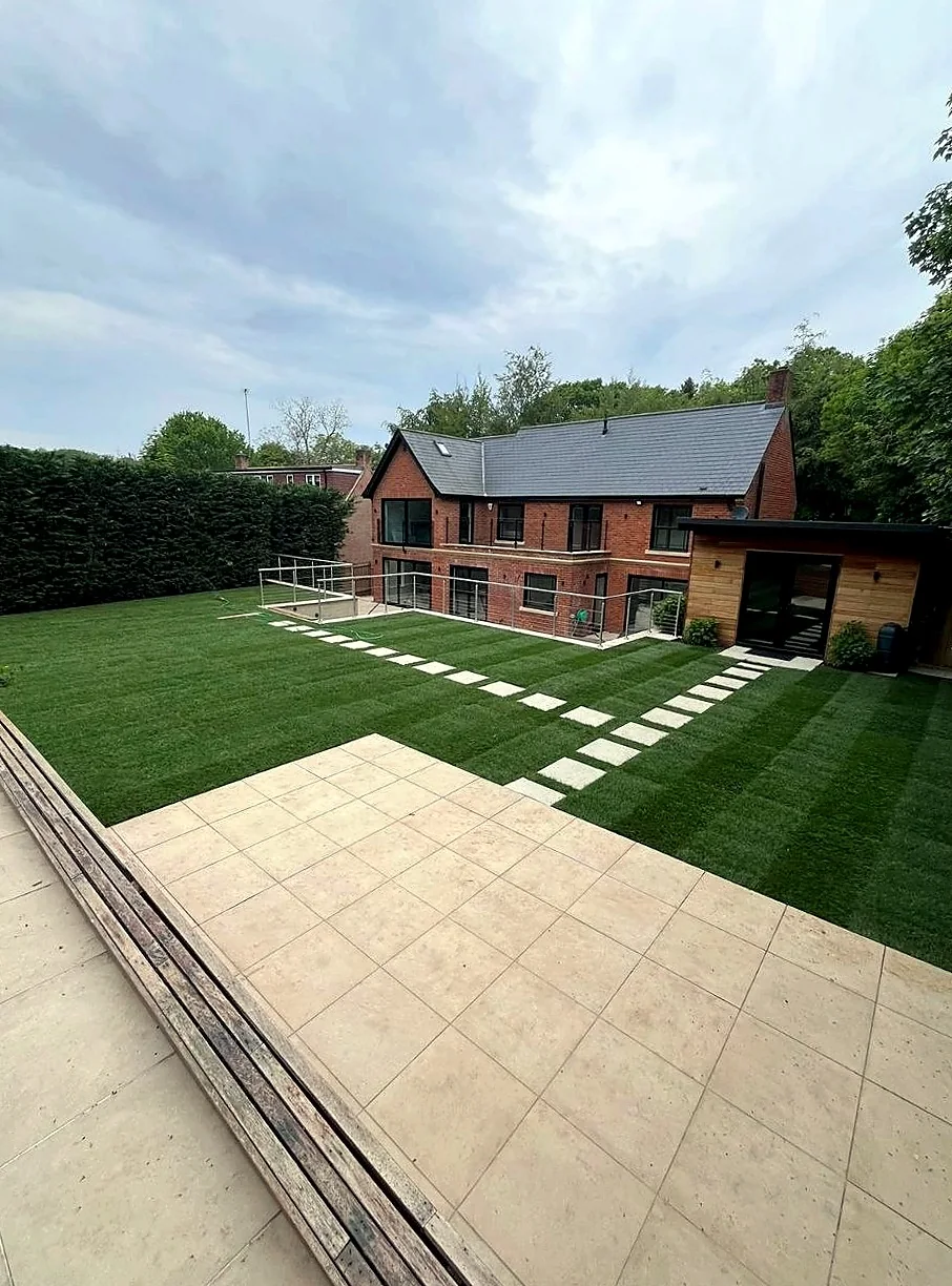 Artificial grass lawn with light stone steppers leading to the house