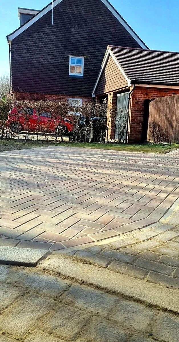 Block paved side driveway leading past a brick barn