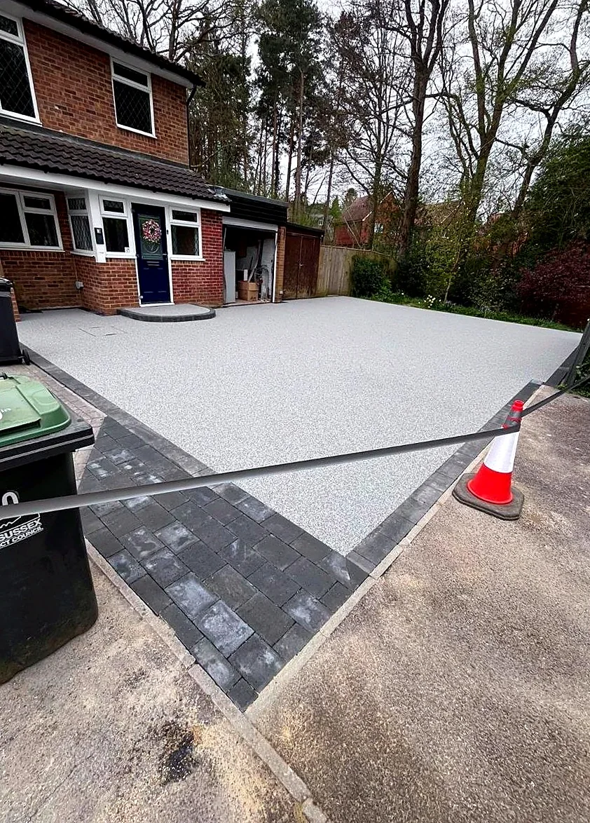Pale resin bound driveway framed by charcoal block edging